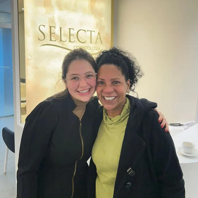 Dentista da Selecta abraçando uma paciente na recepção
