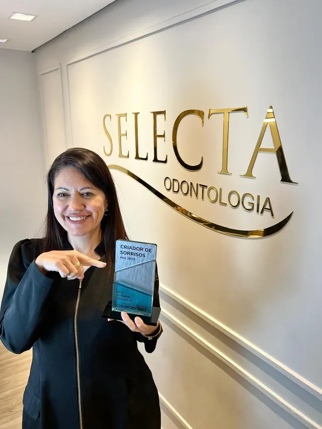 Dentista da Selecta com o troféu na frente do letreiro